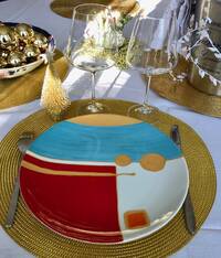 Assiette porcelaine de 26,5 cm de diamètre, un quart peint en rouge carmin avec un motif or et un carré orange, et l’autre moitié peinte en bleu turquoise. Surlignage du motif en relief or.
